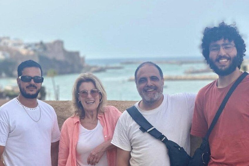 A group of people standing by a coastal area with a rocky shoreline and a clear sky. 2