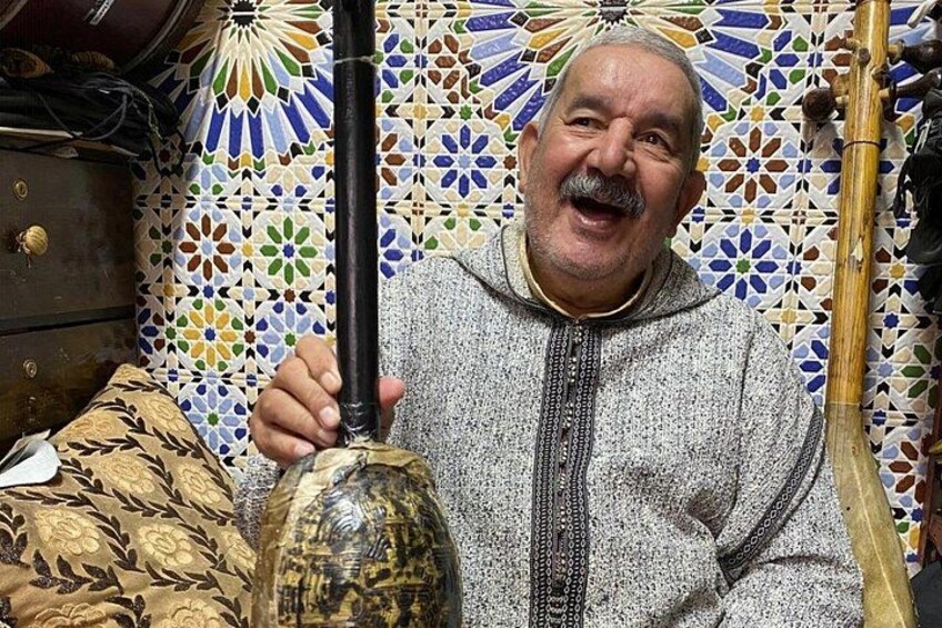 A person holding a traditional musical instrument, a patterned wall, and a decorative bowl. 5