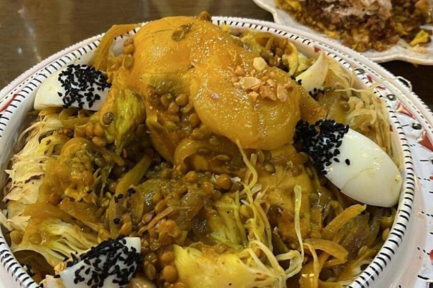 A dish with a roasted chicken, vegetables, and garnishes. 4