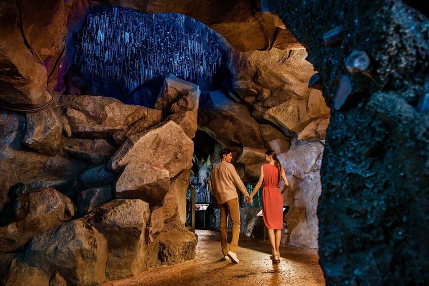 A couple walking through a cave with a waterfall. 4
