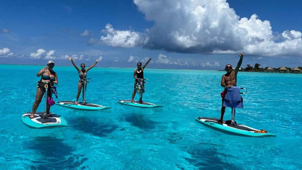 Four people on paddleboards in turquoise water with a clear sky. 4