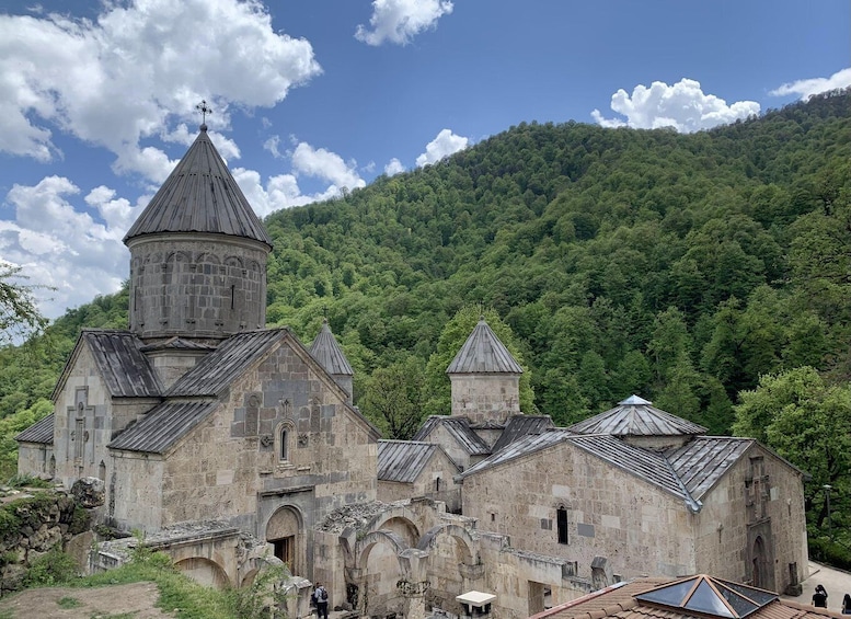 An ancient stone church with a prominent bell tower, surrounded by lush green forest. 3
