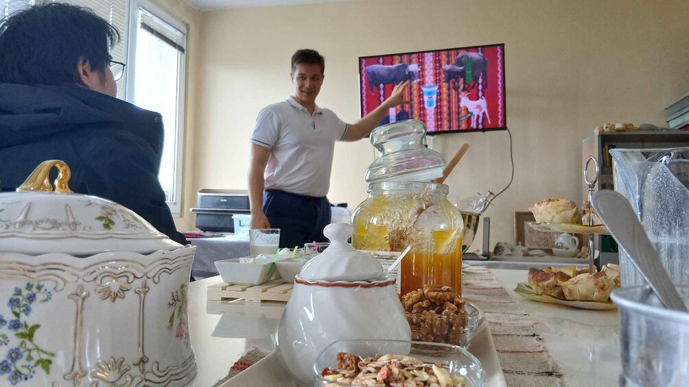 A person serving food at a buffet table with various dishes and a television in the background. 3