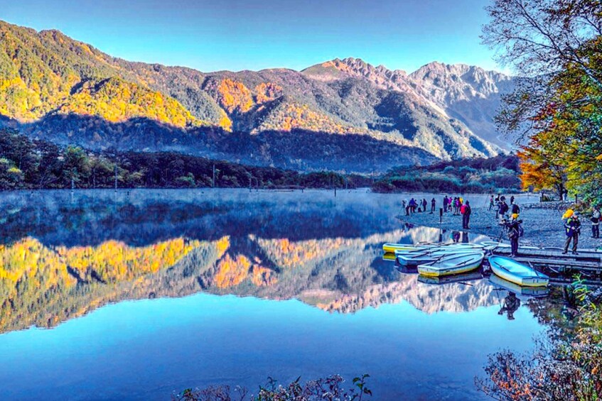 Un lago tranquilo con barcos amarrados en la orilla, rodeado de montañas. 1