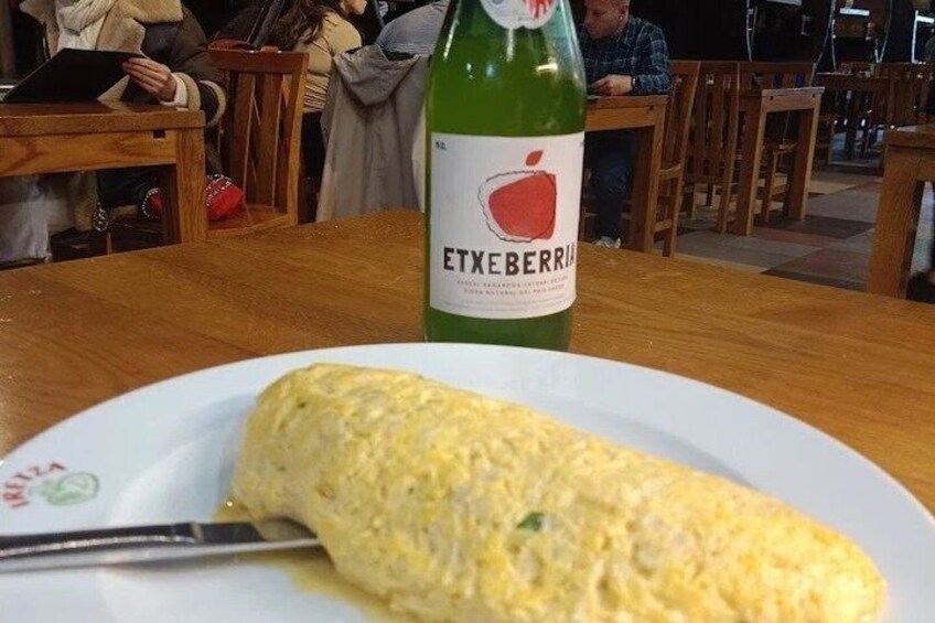En omelet på en tallerken med en flaske Etxeberri vin i baggrunden. 2