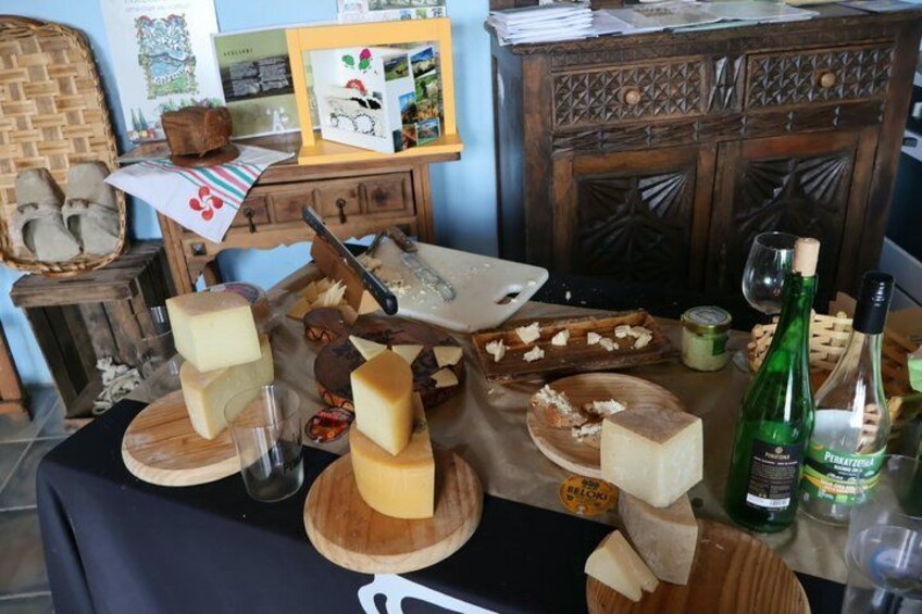 Degustación de quesos con varias variedades sobre tablas de madera, una botella de vino y un rústico armario de madera al fondo. 3