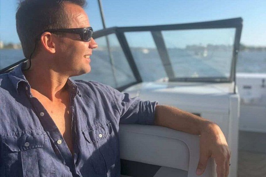 A person sitting on a boat with a view of the water and other boats in the distance. 2