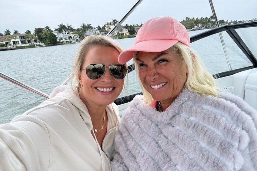 Two people on a boat with a body of water and houses in the background. 3