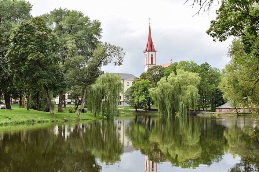 Un lago tranquilo con reflejos de árboles e iglesia de techo rojo. 5