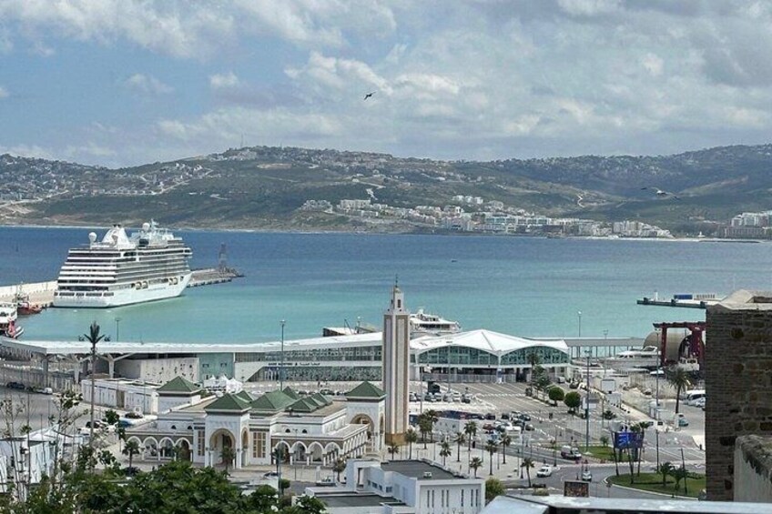 A cruise ship docked at a port with a coastal town and a prominent church in the foreground. 3