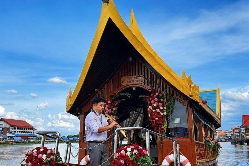A traditional boat with a yellow roof and floral decorations, docked at a waterway with buildings in the background. 3