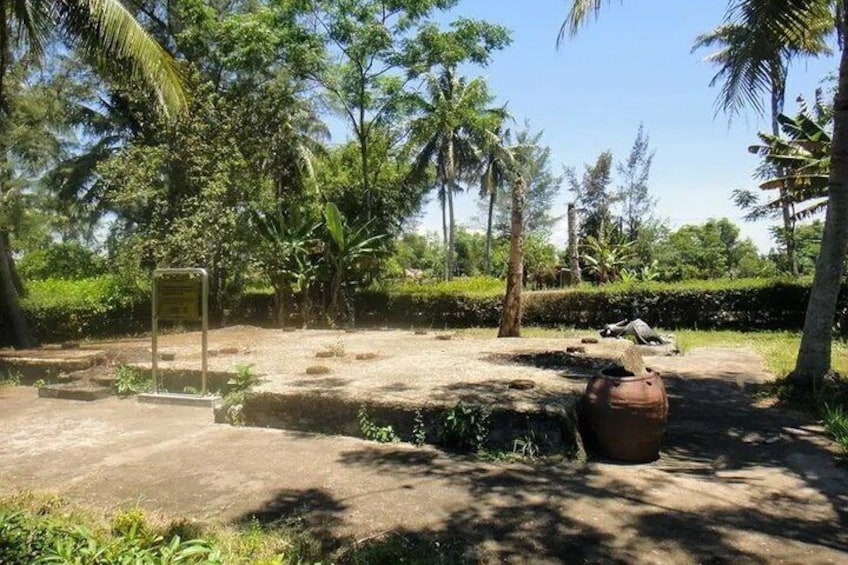 A natural landscape with a large pot, a sign, and a pathway. 1