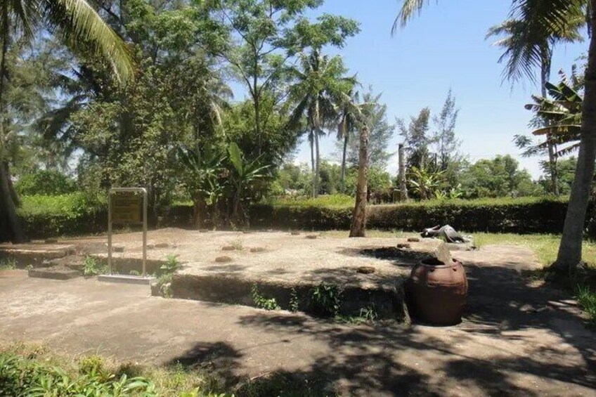 A natural outdoor area with trees, a sign, and a large pot. 3
