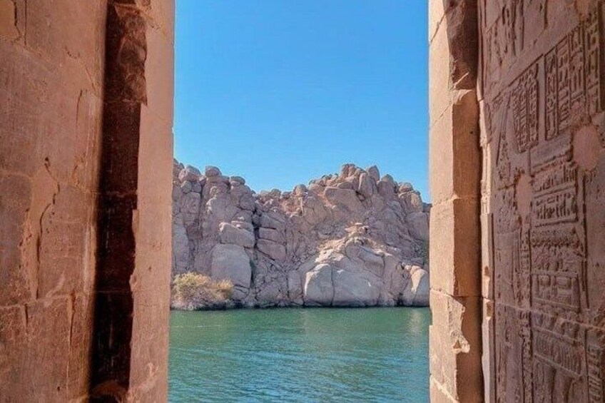 A rock formation with hieroglyphs and a body of water. 1
