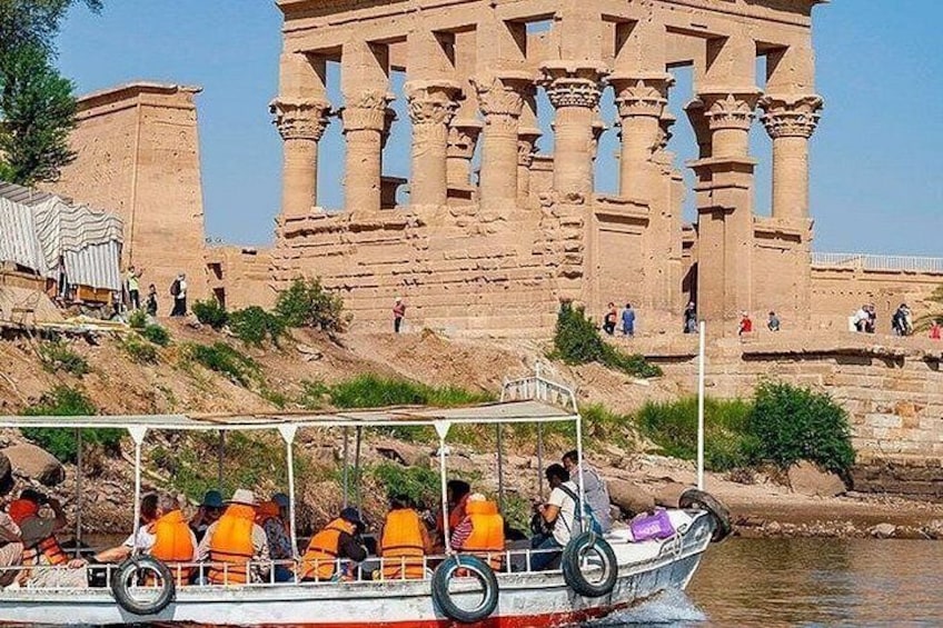 A boat with tourists on a river, ancient ruins in the background. 4