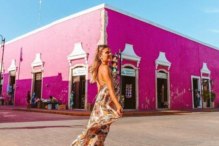 A person walking in front of a pink building with white doors and signs. 2