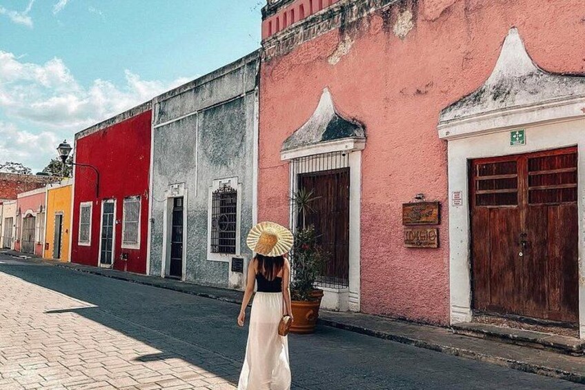 A woman walking down a street lined with colorful buildings. 3