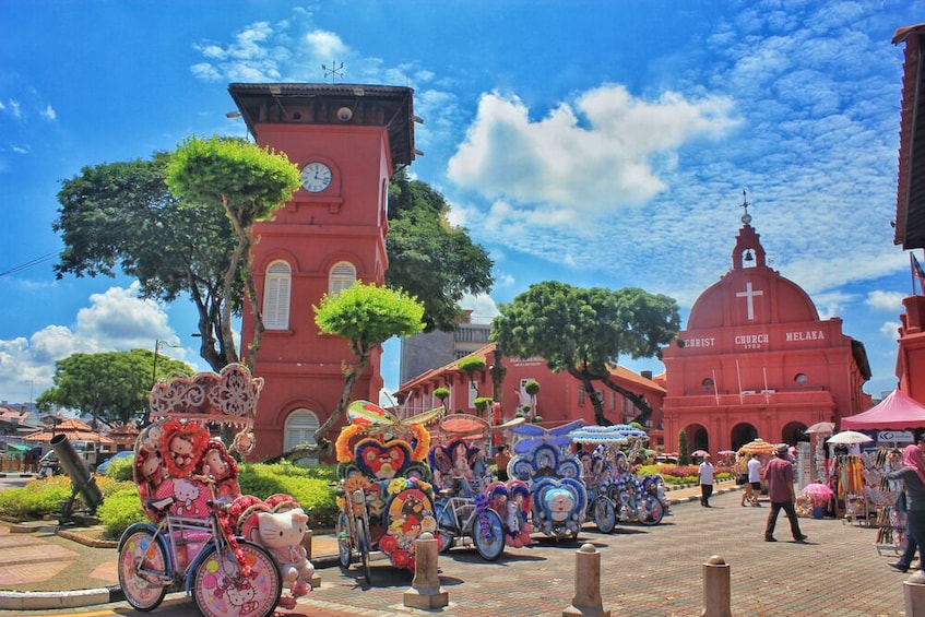 A colorful street with a red church, a clock tower, and a market area. 3