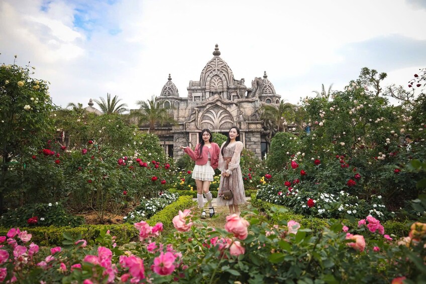 A garden with roses and a historic building in the background. 1