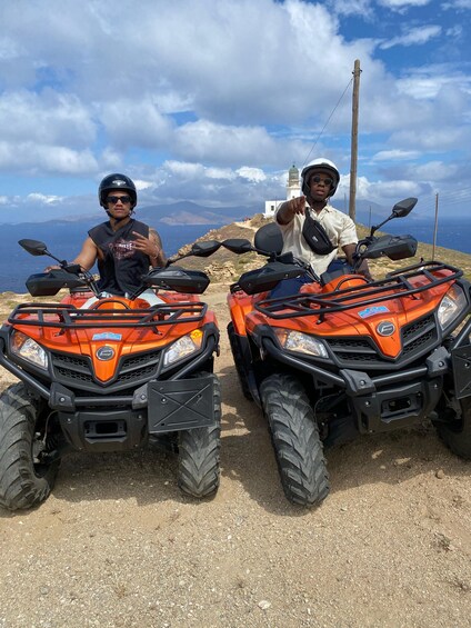 Two individuals on orange off-road vehicles with a coastal landscape in the background. 4