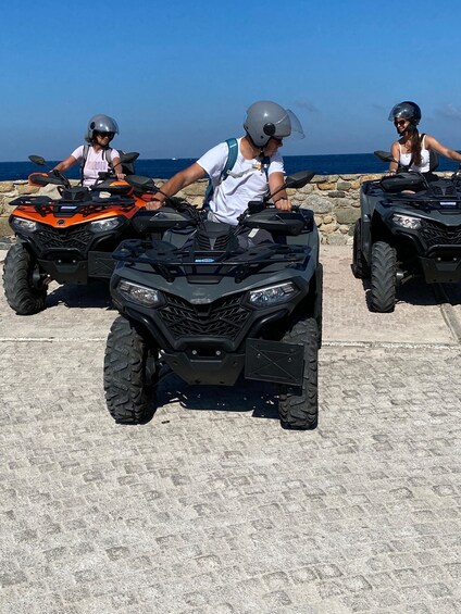 Three people on ATVs on a beach with the ocean in the background. 5