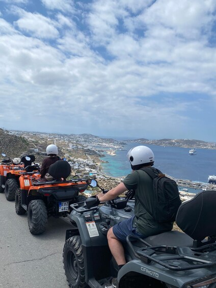A group of people on ATVs on a road with a coastal landscape in the background. 3