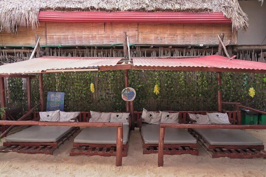 En strandbar med träsolstolar och ett halmtak. 4