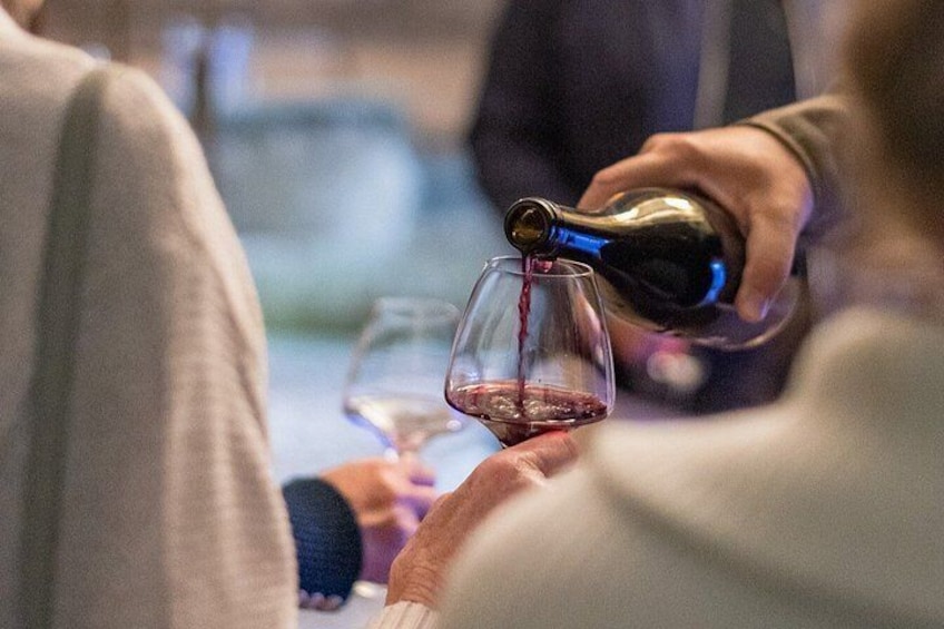 A person pouring red wine into a glass. 2