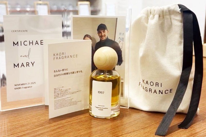 En flaske Kaori Fragrance, et certifikat og en snøret pose på en træoverflade. 2