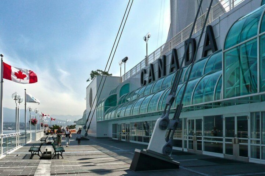 A modern building with 'CANADA' written on it, a Canadian flag, and a clear sky. 1