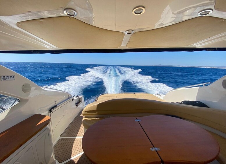 A boat's interior with a view of the ocean and wake behind it. 1