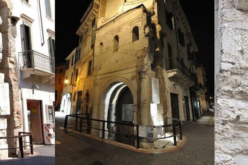 A historic building with arched windows and a balcony, a street with a metal railing, and a white wall. 5