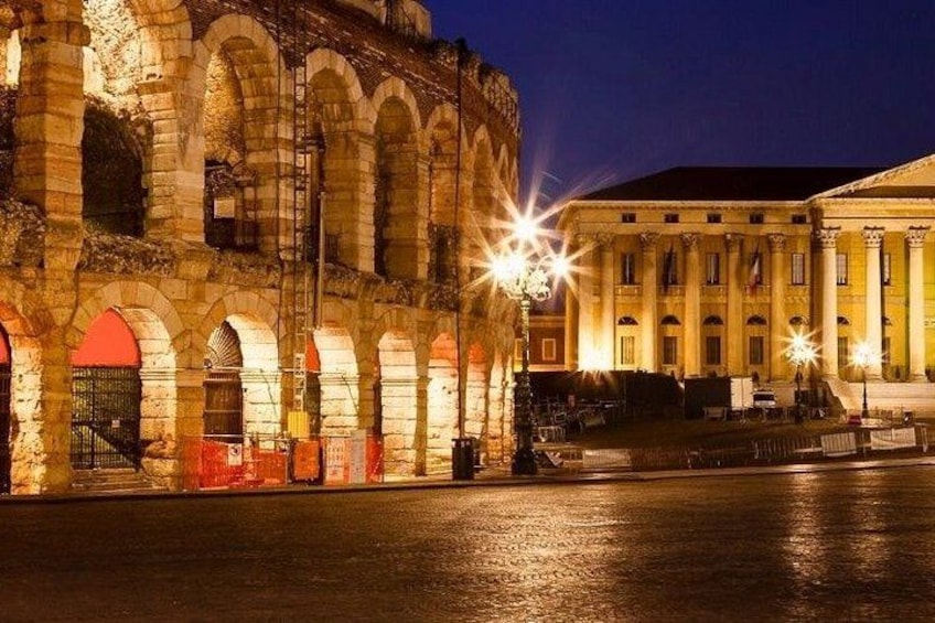 A historic building with arched windows and columns, illuminated by street lamps at night. 1