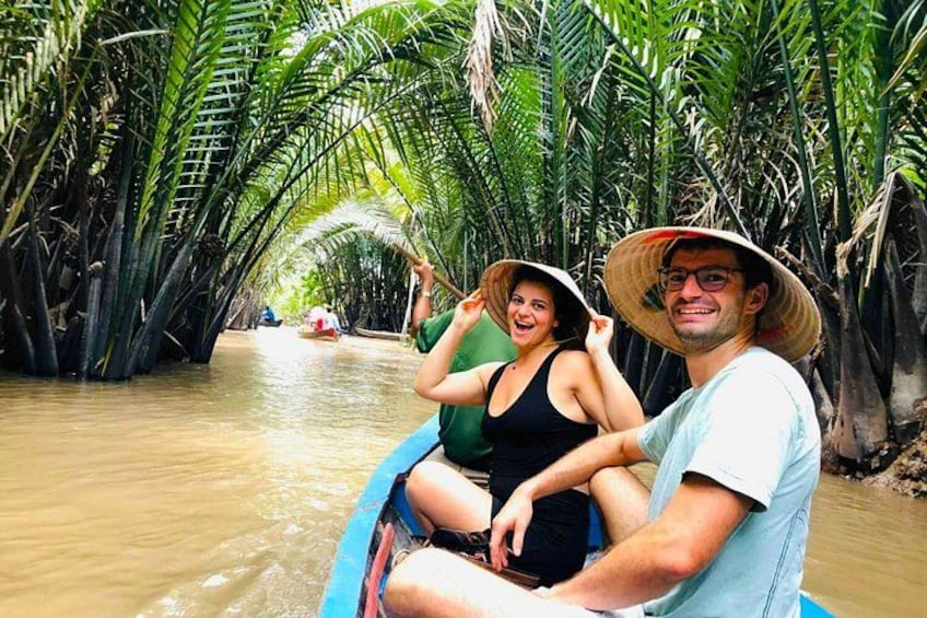 A couple in a boat navigating a waterway surrounded by tall palm trees. 3