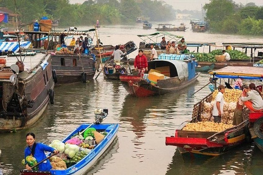 A river with boats carrying goods, people on the boats, and a dock in the background. 1