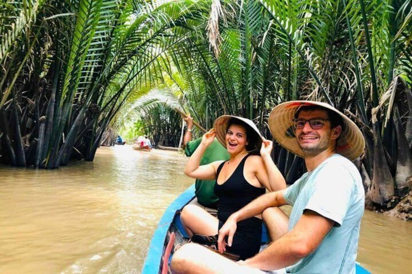 A couple in a boat navigating a waterway surrounded by palm trees. 3