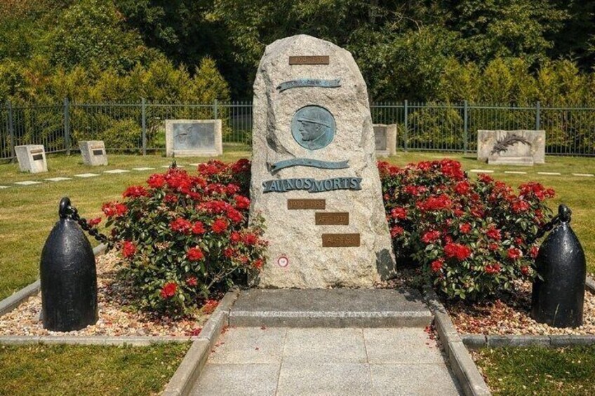 Une pierre tombale portant l’inscription « ALLNOSMORTS » et la date « 1913-1914 », entourée de fleurs rouges et de deux objets sphériques noirs. 3