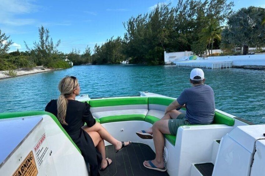 Due persone su una barca gonfiabile verde e bianca su acqua calma, con un molo e alberi sullo sfondo. 2