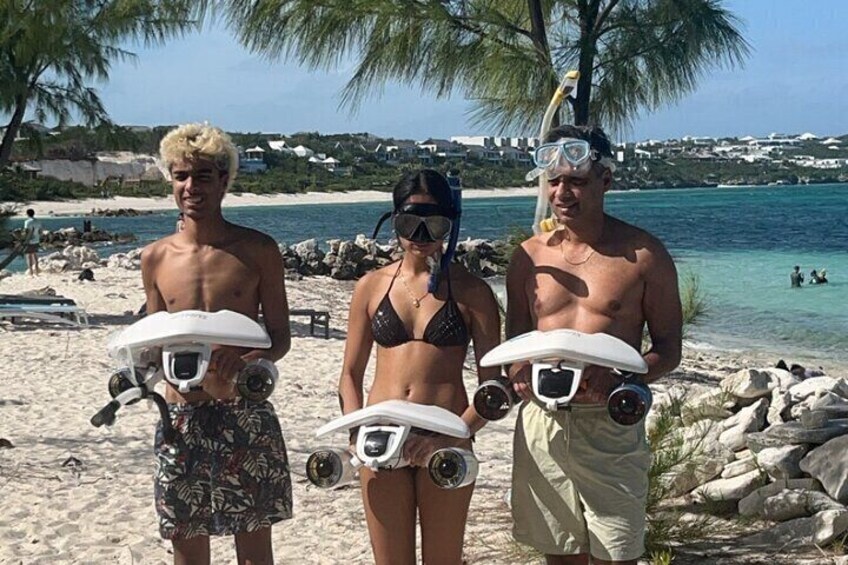 Tre persone su una spiaggia con maschere e pinne, cielo sereno e mare calmo. 3