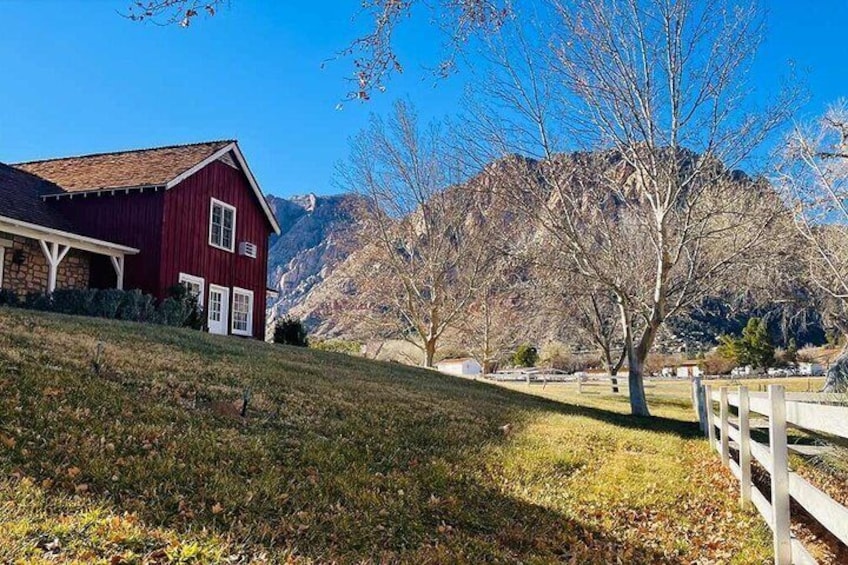 A red barn on a grassy hill with mountains in the background. 1