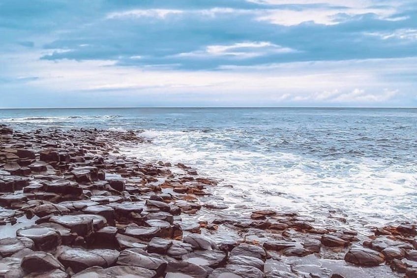 A rocky shoreline with waves crashing onto the rocks. 4