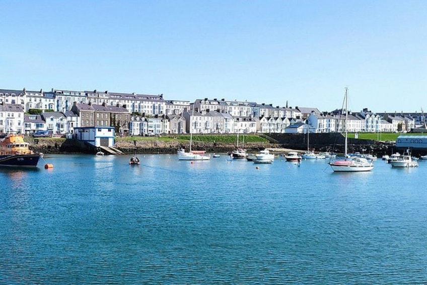 A harbor with boats, a lighthouse, and a row of houses along the shore. 5