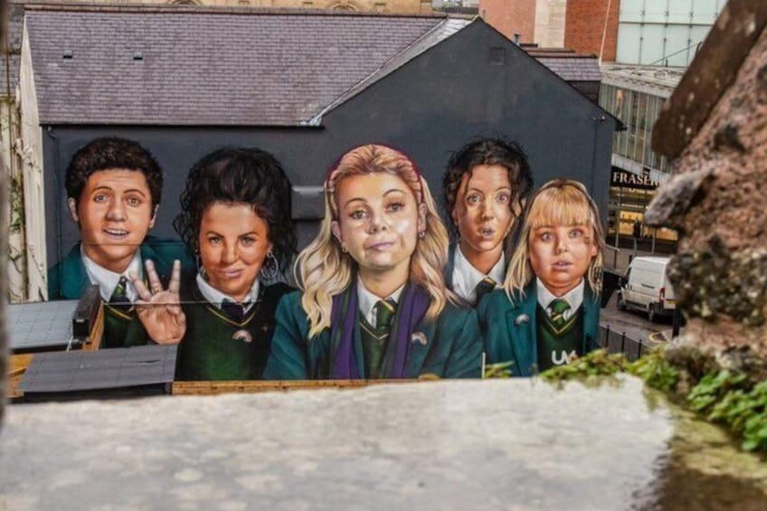 A mural of five people in school uniforms with a building in the background. 1