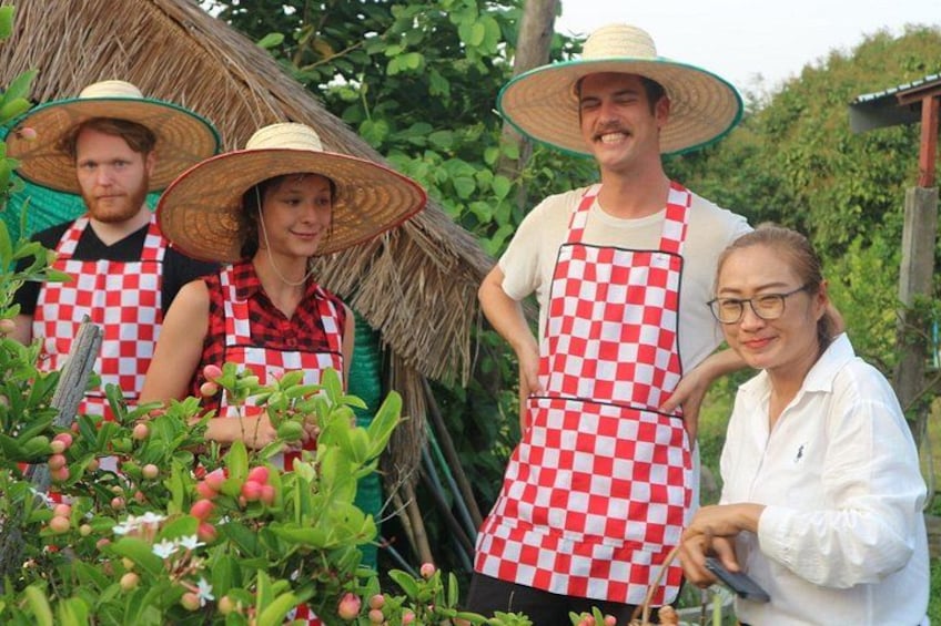 Personas con delantales a cuadros y sombreros de paja en un jardín con plantas. 4