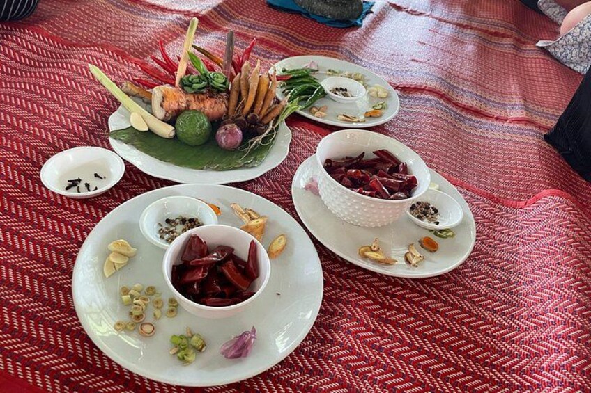 Una mesa con varios platos, incluyendo un plato central con pescado, rodeado de platos más pequeños con salsas y verduras. 3