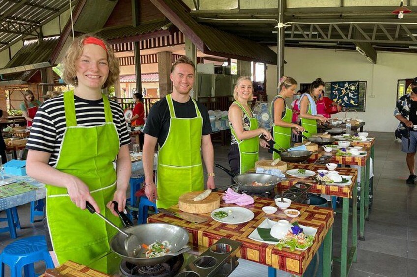 People cooking at a market stall with various dishes and cooking utensils. 1