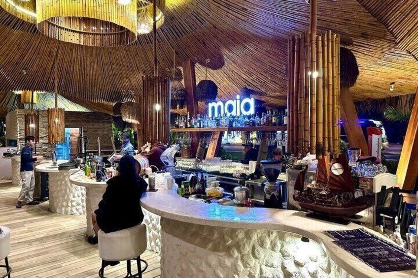 A bar with a bamboo ceiling, a sign reading 'maia,' and a ship model. 2