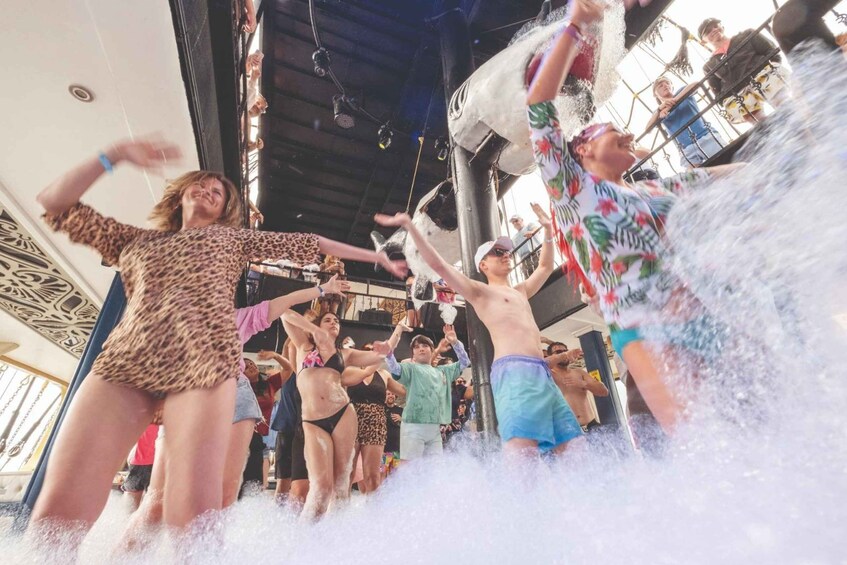 People enjoying a water activity, likely a water slide or splash zone, with a crowd and a covered structure overhead. 5