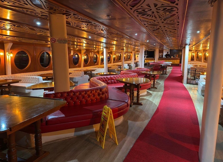 A restaurant interior with red leather booths, wooden tables, and ornate ceiling designs. 2