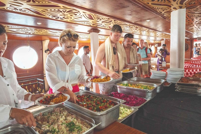 A buffet with various food options, people serving themselves, and a decorative ceiling. 3